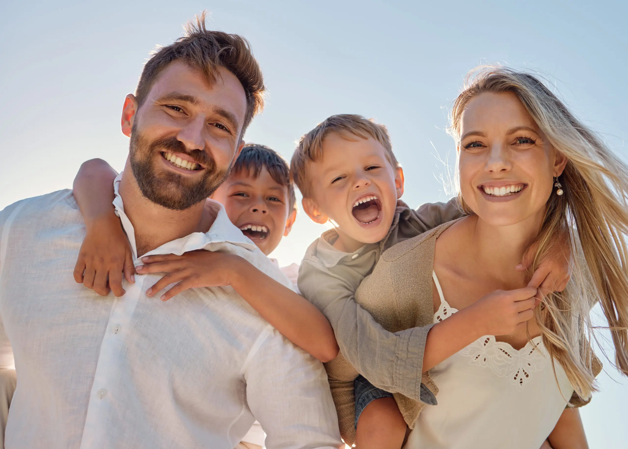 Happy family, portrait and beach with happy, smile and relax mother and father hug, embrace and laughing together. Kids, face and parents on sea vacation with family bonding, excited and cheerful